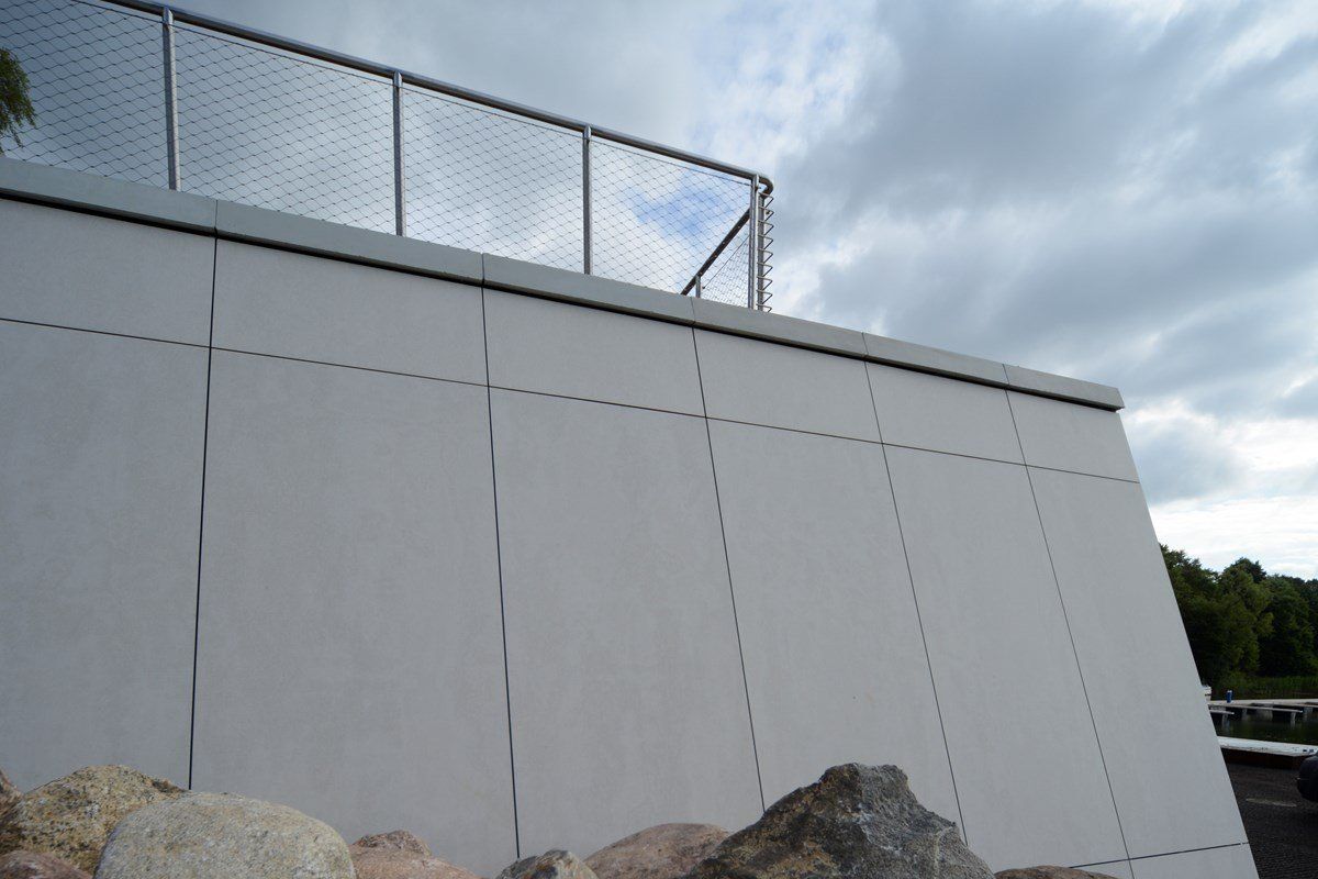 White wall with a metal railing and cloudy sky.