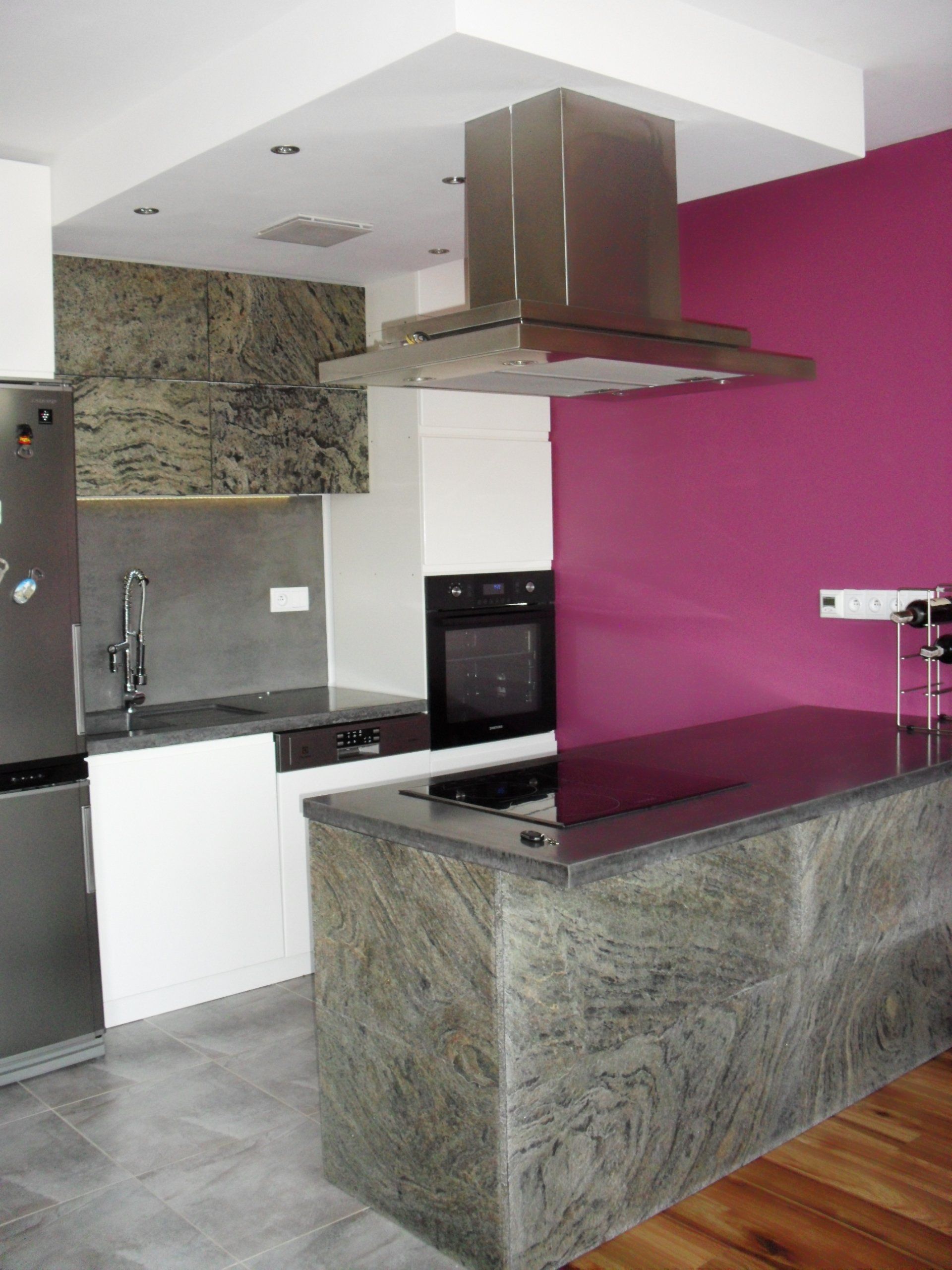 Modern kitchen with stainless steel appliances, granite countertops, and a magenta accent wall.