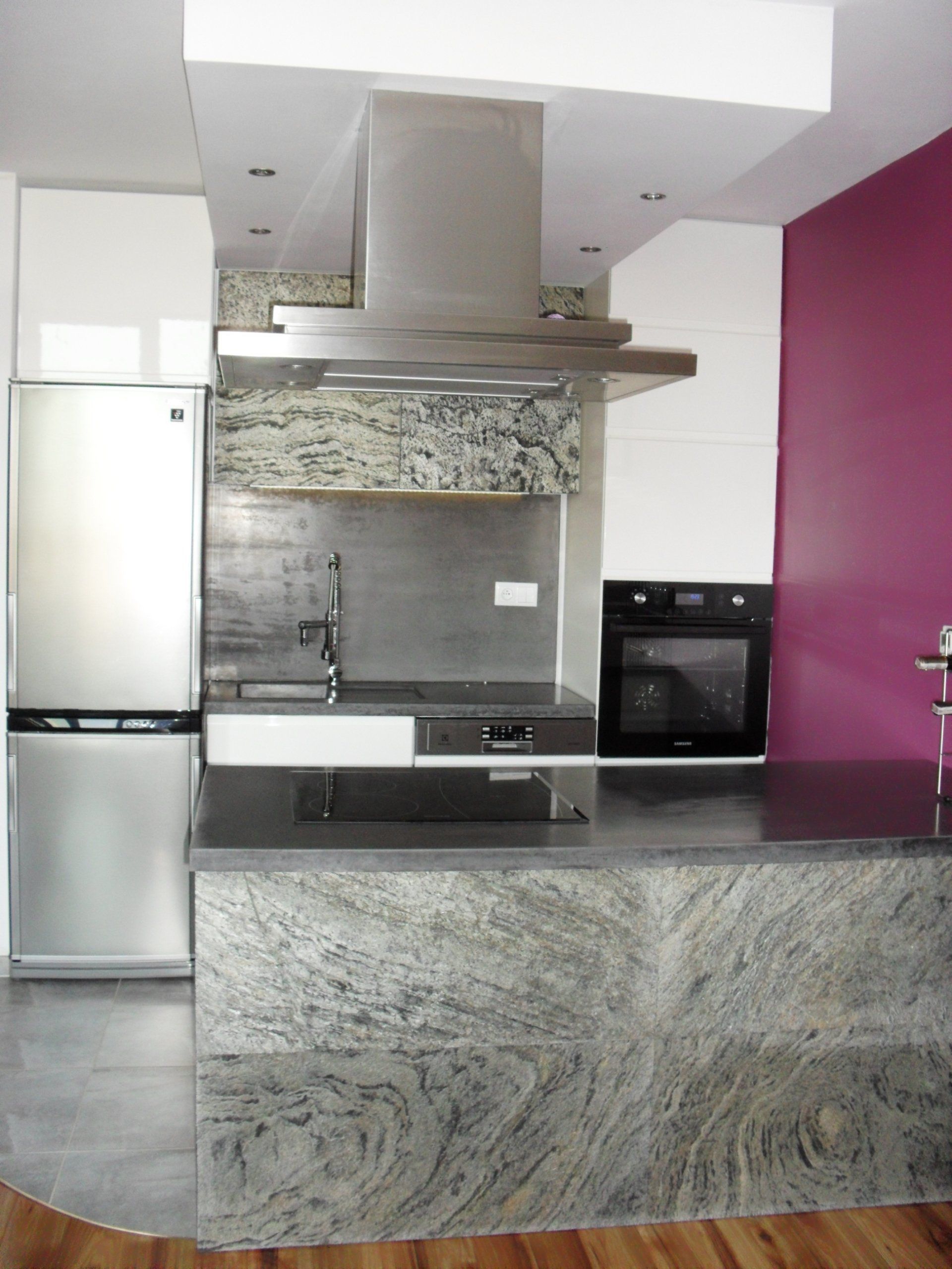 Modern kitchen with stainless steel appliances, granite countertops, and a purple accent wall.