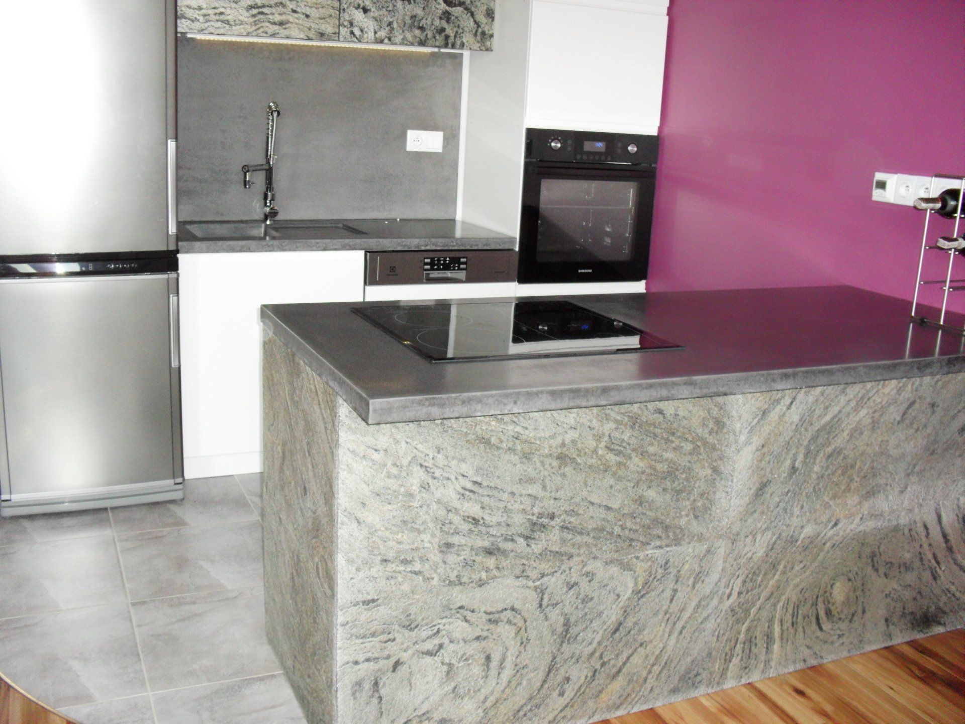 Modern kitchen with stainless steel appliances, granite countertops, and an island with a stovetop.