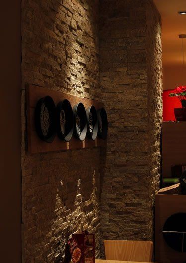 Stone wall with mounted black objects. Wooden table and restaurant setting. Warm lighting.
