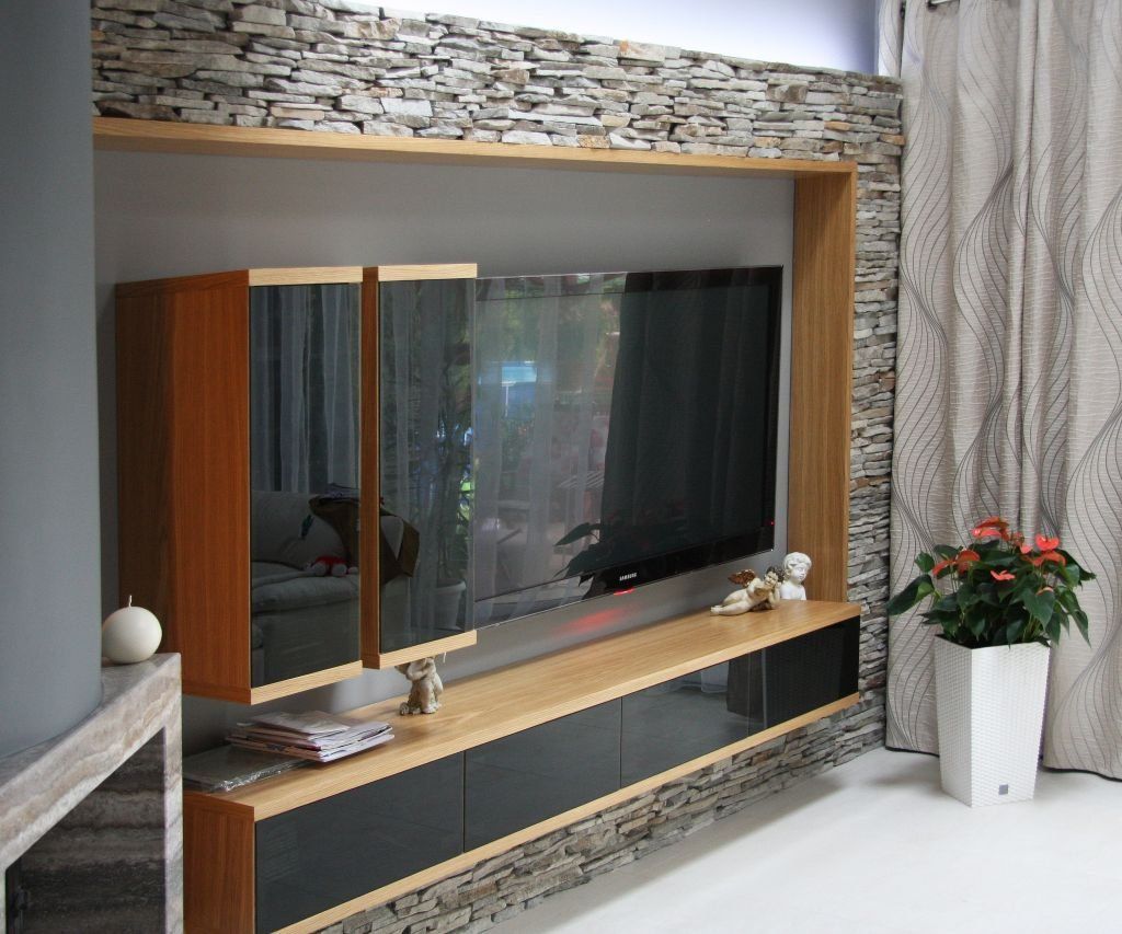 Built-in entertainment center with a large TV, wood, stone accents, and cabinets; a plant in a white pot.
