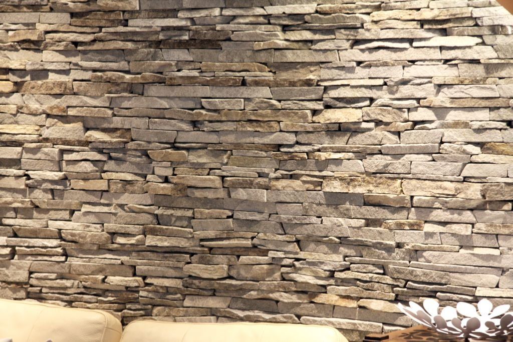 Stone wall with rough, horizontal rectangular pieces. Beige and gray hues.