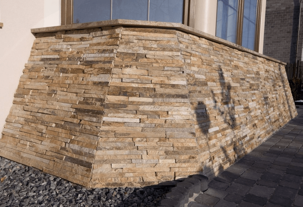 Stone wall with angled corner, beige and gray tones, beneath a window.