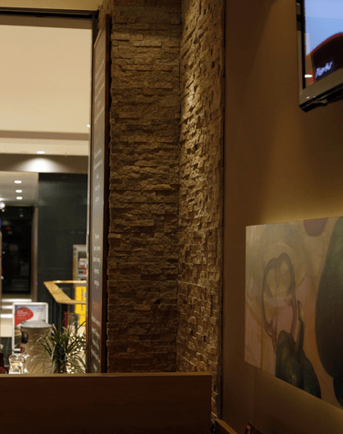 Stone accent wall inside a building, next to a window and art.