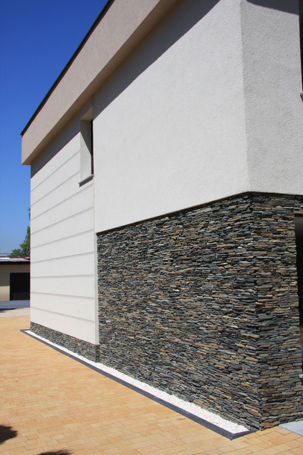 Modern building with stone facade and light stucco walls on a sunny day.