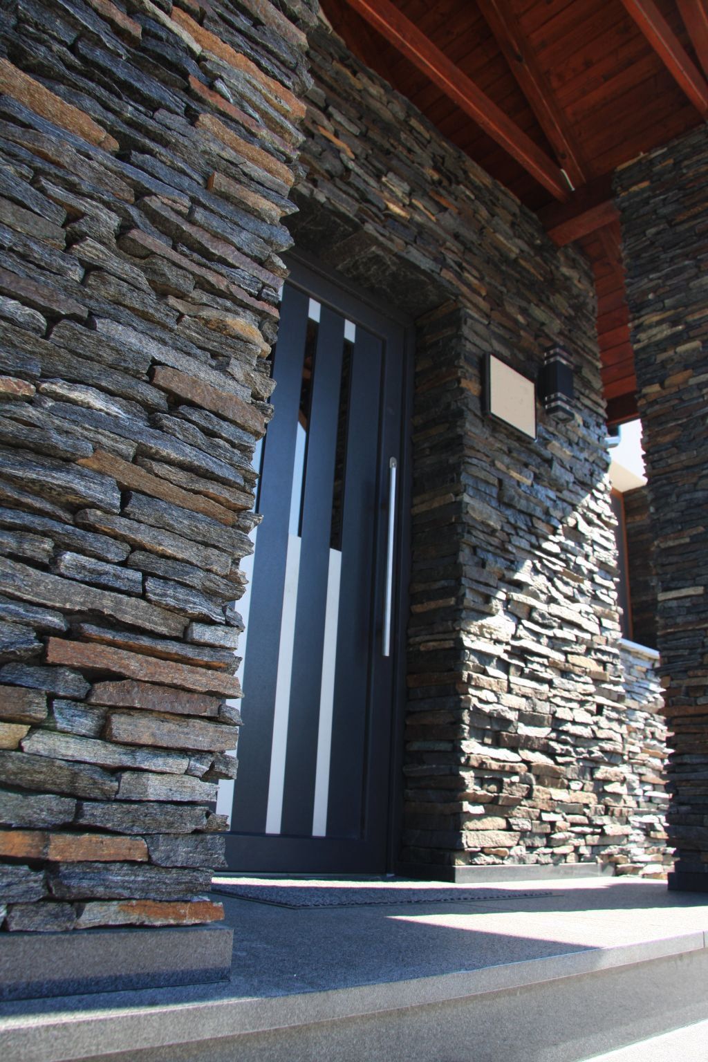 Stone facade entrance with dark doors and white vertical accents.
