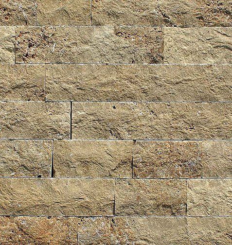 Close-up of a wall made of rectangular, light brown stone bricks.