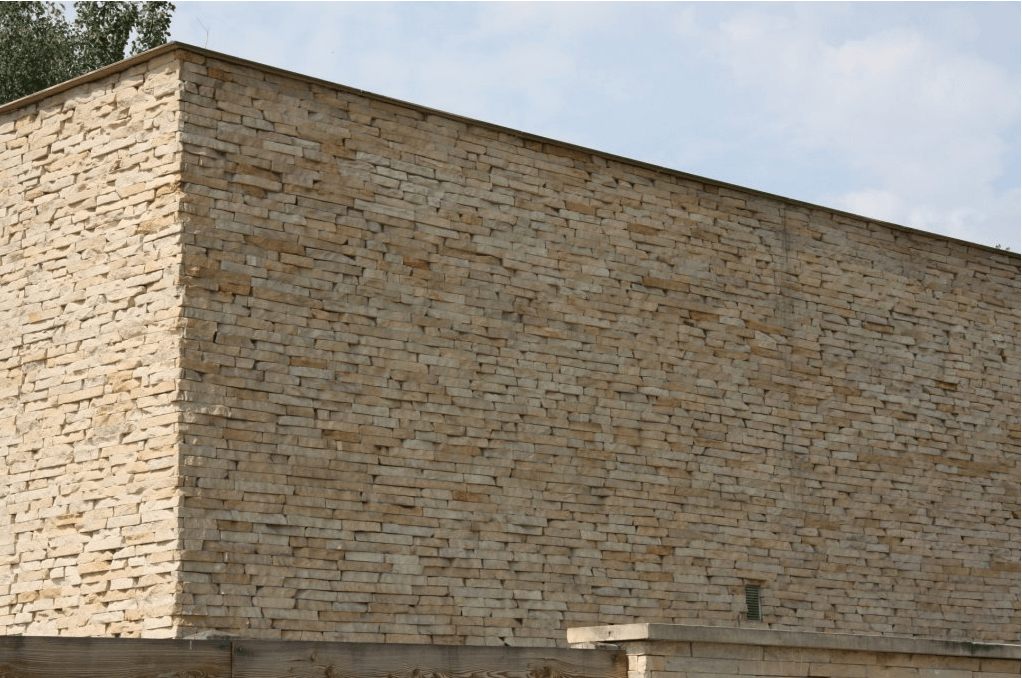 Stone building exterior with light brown stone blocks, blue sky.