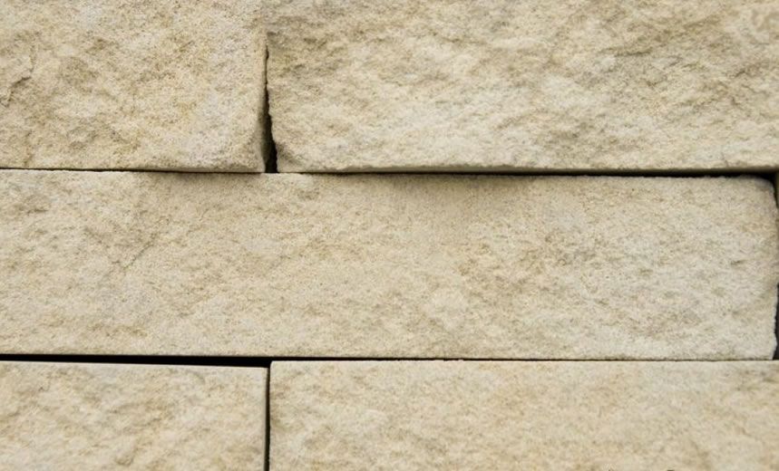 Beige rectangular stone bricks in a stacked wall pattern.