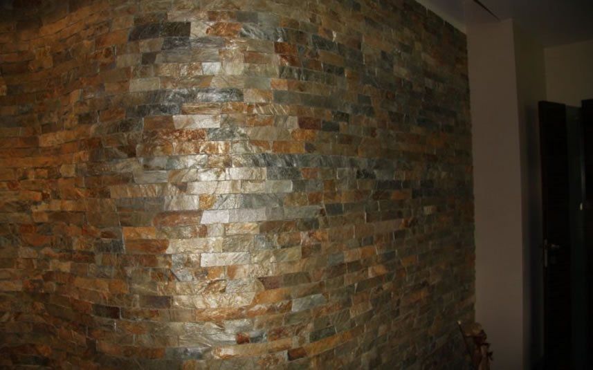 Corner of a wall with layered stone, featuring brown, gold, and gray tones.