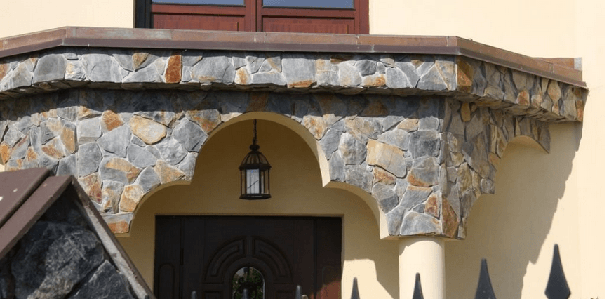 Stone facade above a dark door with an arch, an exterior lantern hangs from the ceiling.