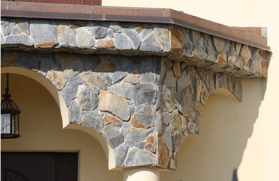 Stone facade with arches and a bronze-colored overhang on a building.
