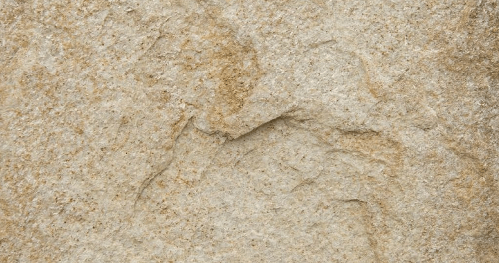Close-up of a rough, beige stone surface with subtle texture and cracks.