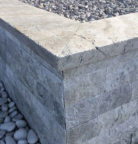 Stone-clad retaining wall with gravel fill; gray and tan hues.