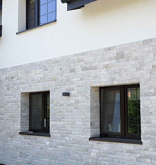 Light-colored brick facade with dark-framed windows in a building.