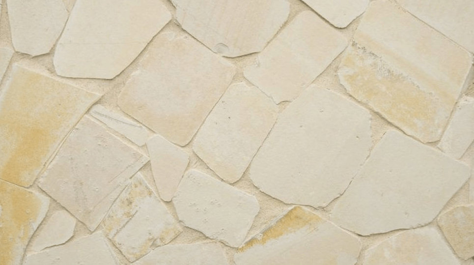 Tan and beige stone wall with irregular, flat-cut pieces and visible grout lines.