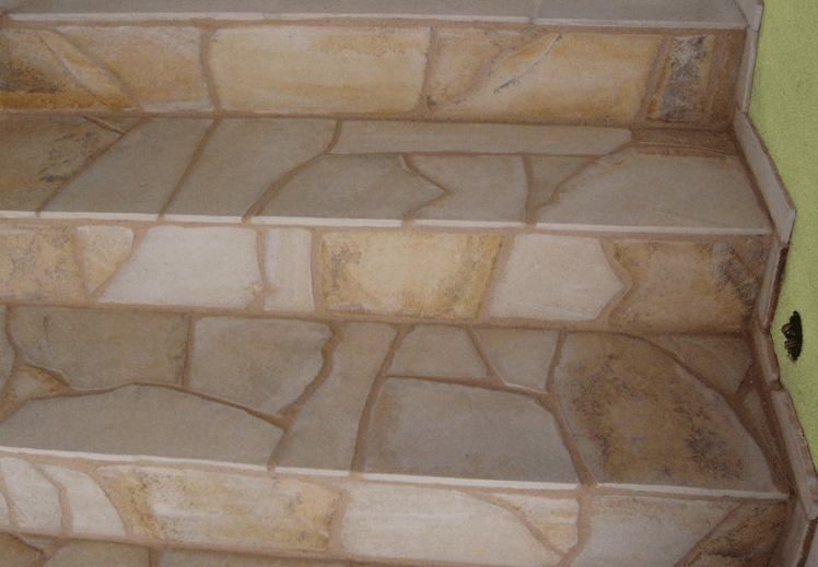 Stone steps with irregular, tan-colored tiles.