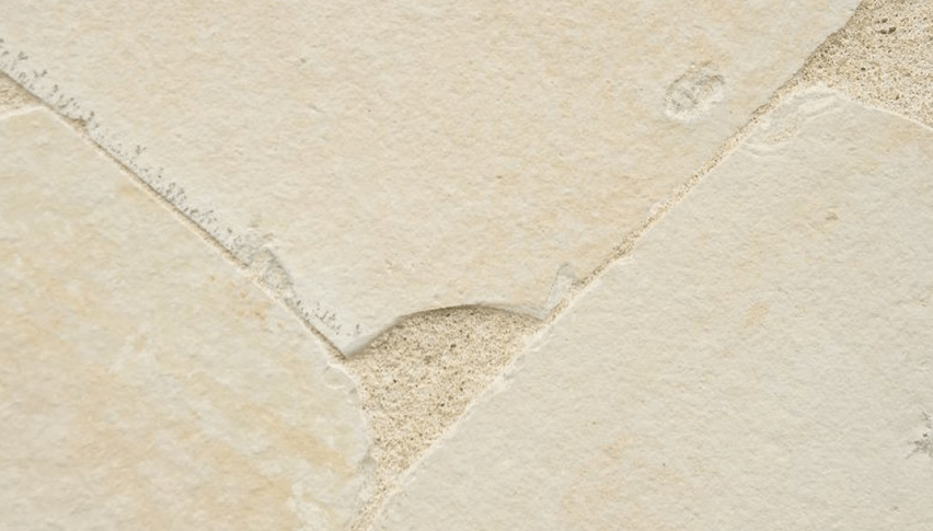 Beige stone tiles with rough edges and textured grout.