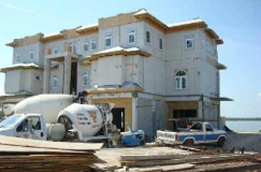A large house under construction with a concrete mixer in front of it