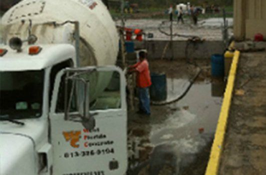 A man is standing next to a concrete mixer truck