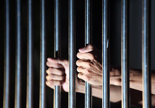 Person holding bars in jail waiting on bail bond in Waterbury Person holding bars in jail waiting on bail bond in Waterbury