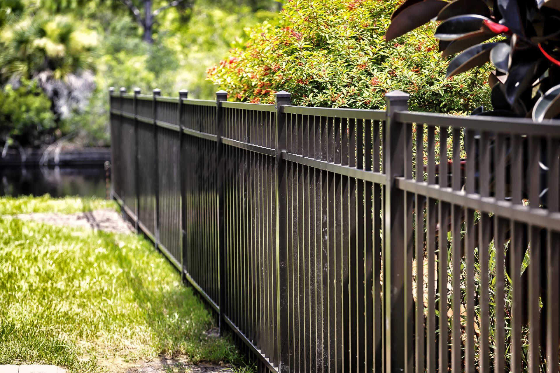 A long metal fence surrounds a lush green yard.