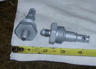two pieces of metal are sitting on top of a piece of paper next to a tape measure .