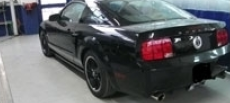 Ford Mustang coupé nera in un garage, vista posteriore a tre quarti