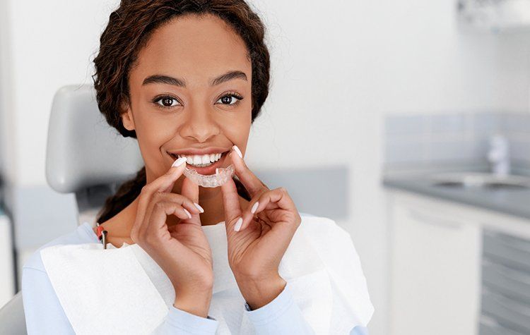 Woman Holding Invisible Aligner — Liberty, MO — Triplett Dental