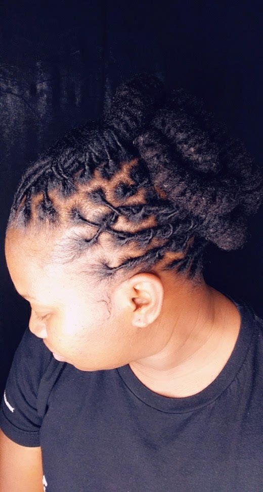 Side profile of a woman with braided hair wearing a black shirt against a dark background