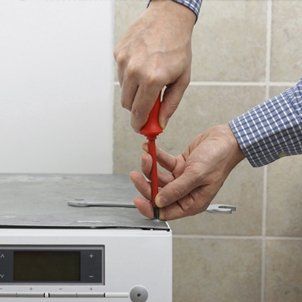 Technician servicing washing machine using screwdriver - Barbecue Care in South Jersey, NJ