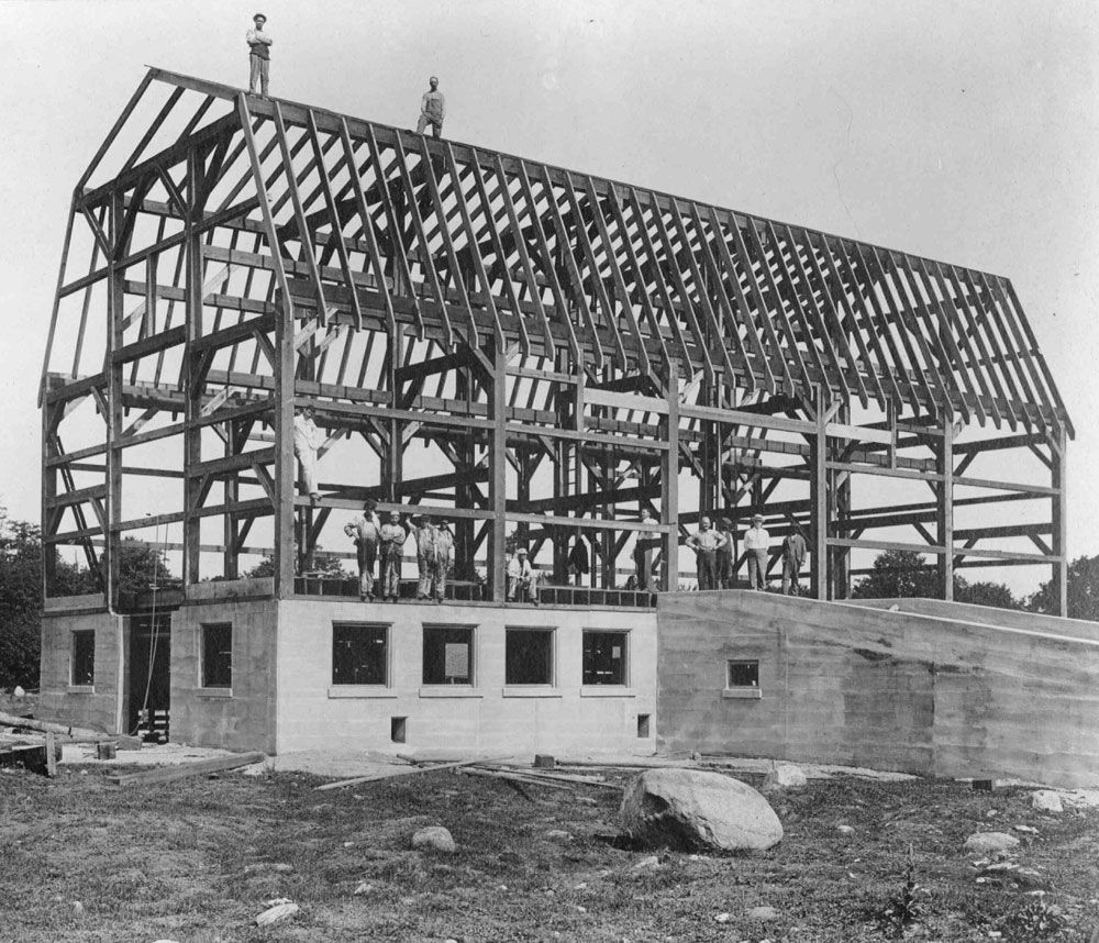 This photograph shows the construction of the cow barn at the Huronia Regional Centre farm. The barn’s concrete foundations have been poured and a wooden frame has been constructed. Workers can be seen sitting and standing on the foundations and the wooden beams of the frame. Under J.P. Downey’s tenure as Superintendent, the institution farm was expanded by 270 acres. Almost all work at the farm was carried out using the unpaid labour of residents. Image from the Regional Centre Records.) This photograph shows the construction of the cow barn at the Huronia Regional Centre farm. The barn’s concrete foundations have been poured and a wooden frame has been constructed. Workers can be seen sitting and standing on the foundations and the wooden beams of the frame. Under J.P. Downey’s tenure as Superintendent, the institution farm was expanded by 270 acres. Almost all work at the farm was carried out using the unpaid labour of residents. Image from the Regional Centre Records.)