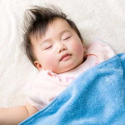 A baby is sleeping under a blue blanket