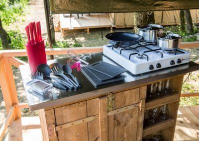 Buitenkeuken met houten aanrechtblad, gasfornuis, kookgerei en keukengerei op de veranda