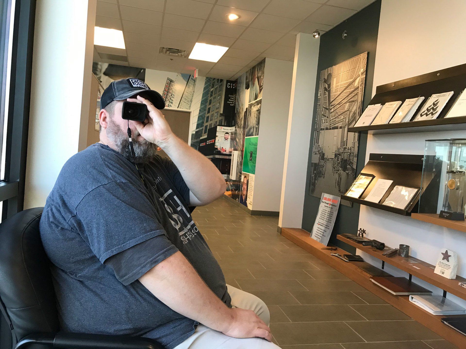playful man looking through photography loop, inside office and manufacturing building, (texas nameplate company)