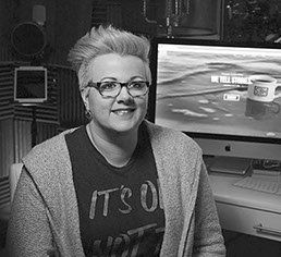 sound proofing walls, cardioid microphone with pop filter, ipad stand, apple imac, desk, lamp, woman platinum hair, pompador, edgy, tshirt and sheater, dark glasses