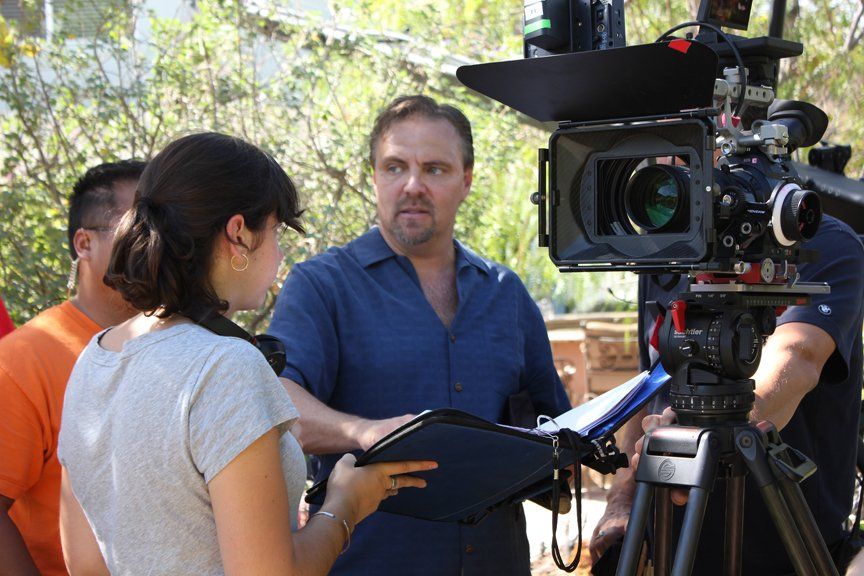a man who's the director standing next to the camera talking to crew