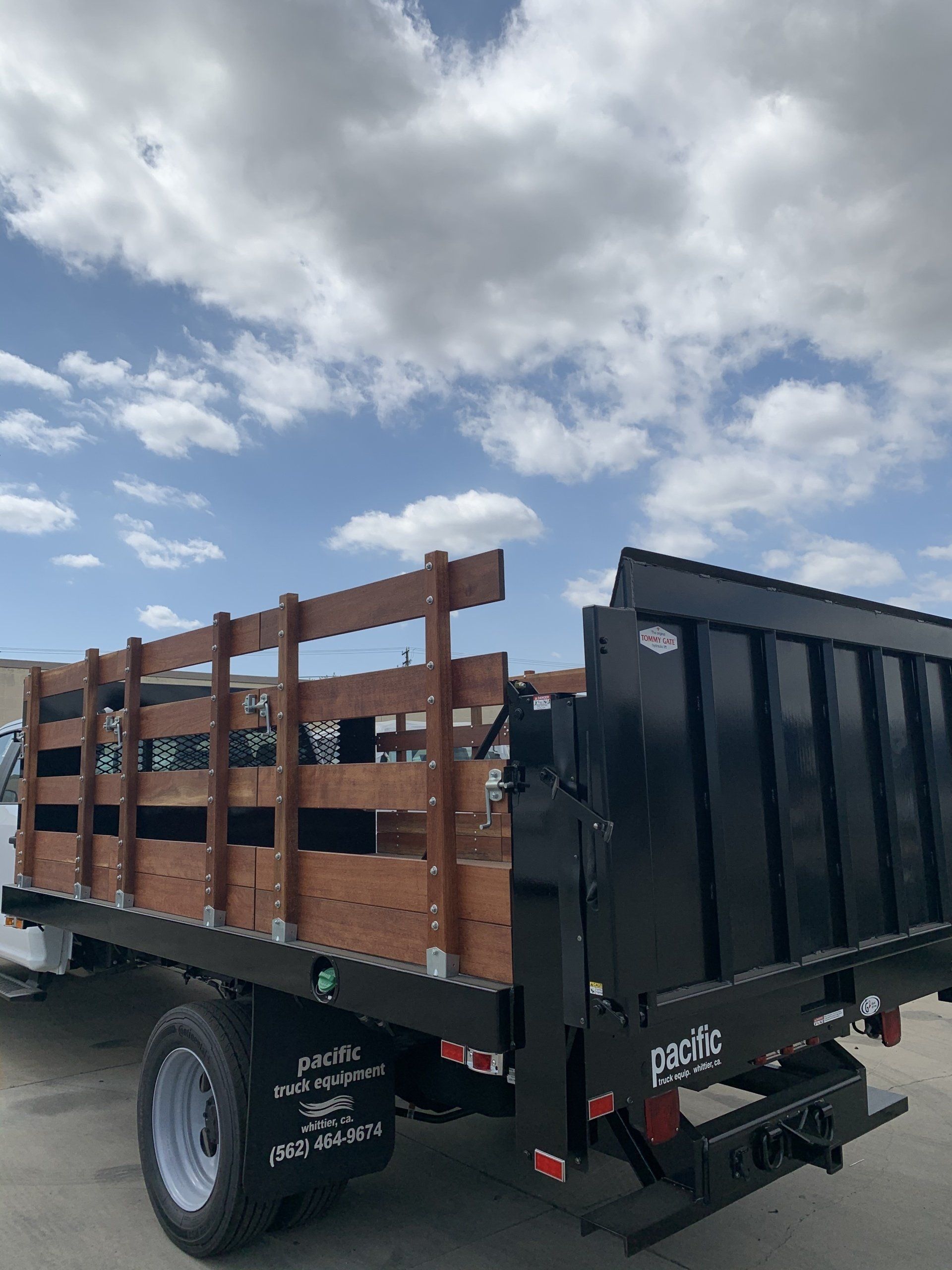 Black dump truck with wooden sideboards on a cloudy day.