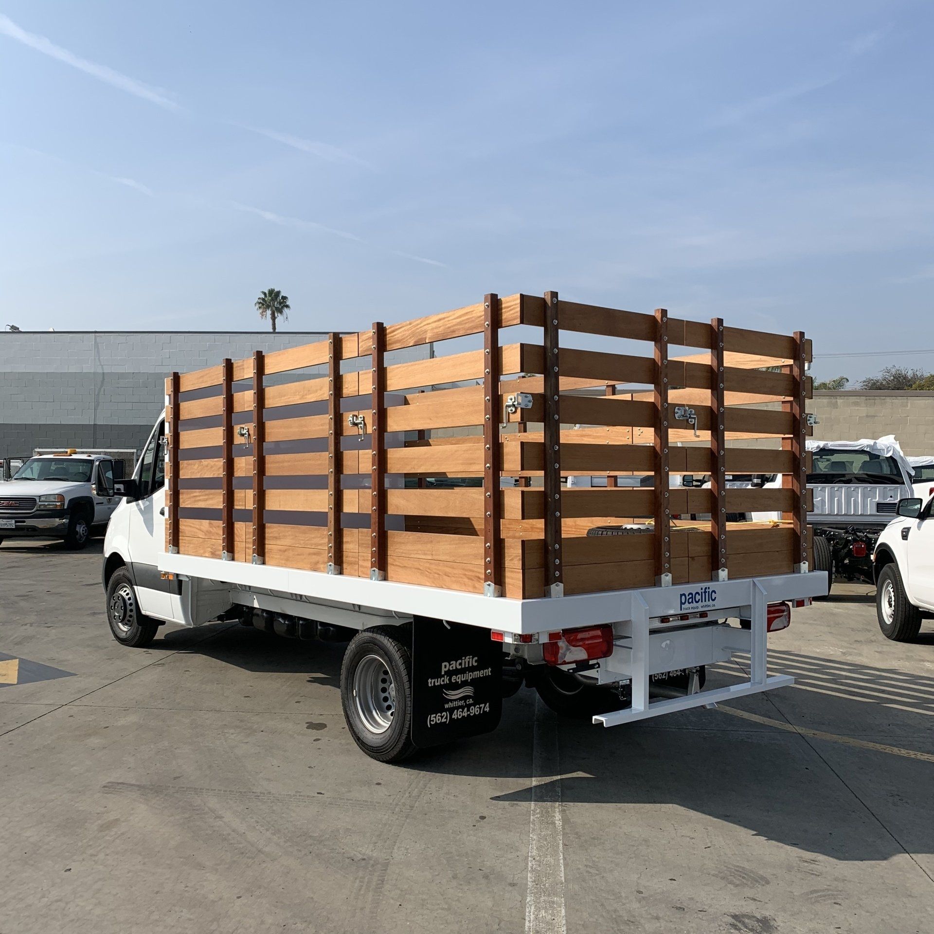 White flatbed truck with wooden sides in a parking lot.