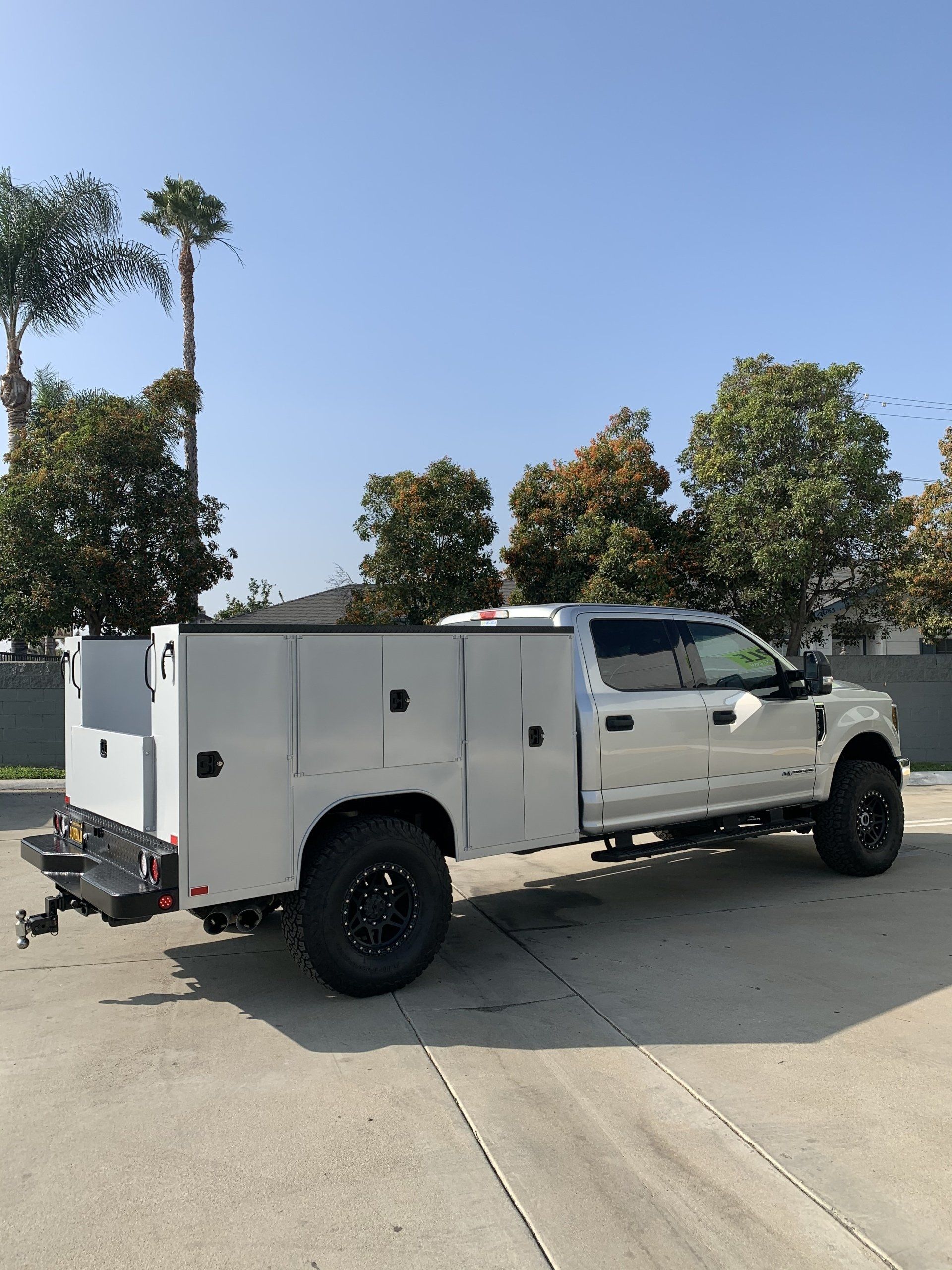 White utility truck with black wheels parked outdoors on a sunny day.