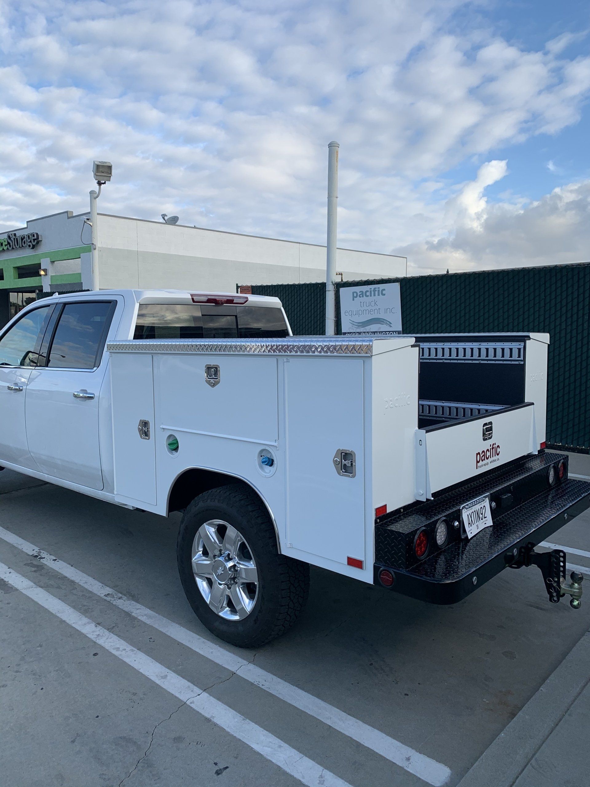 White pickup truck with utility bed parked in a parking lot.