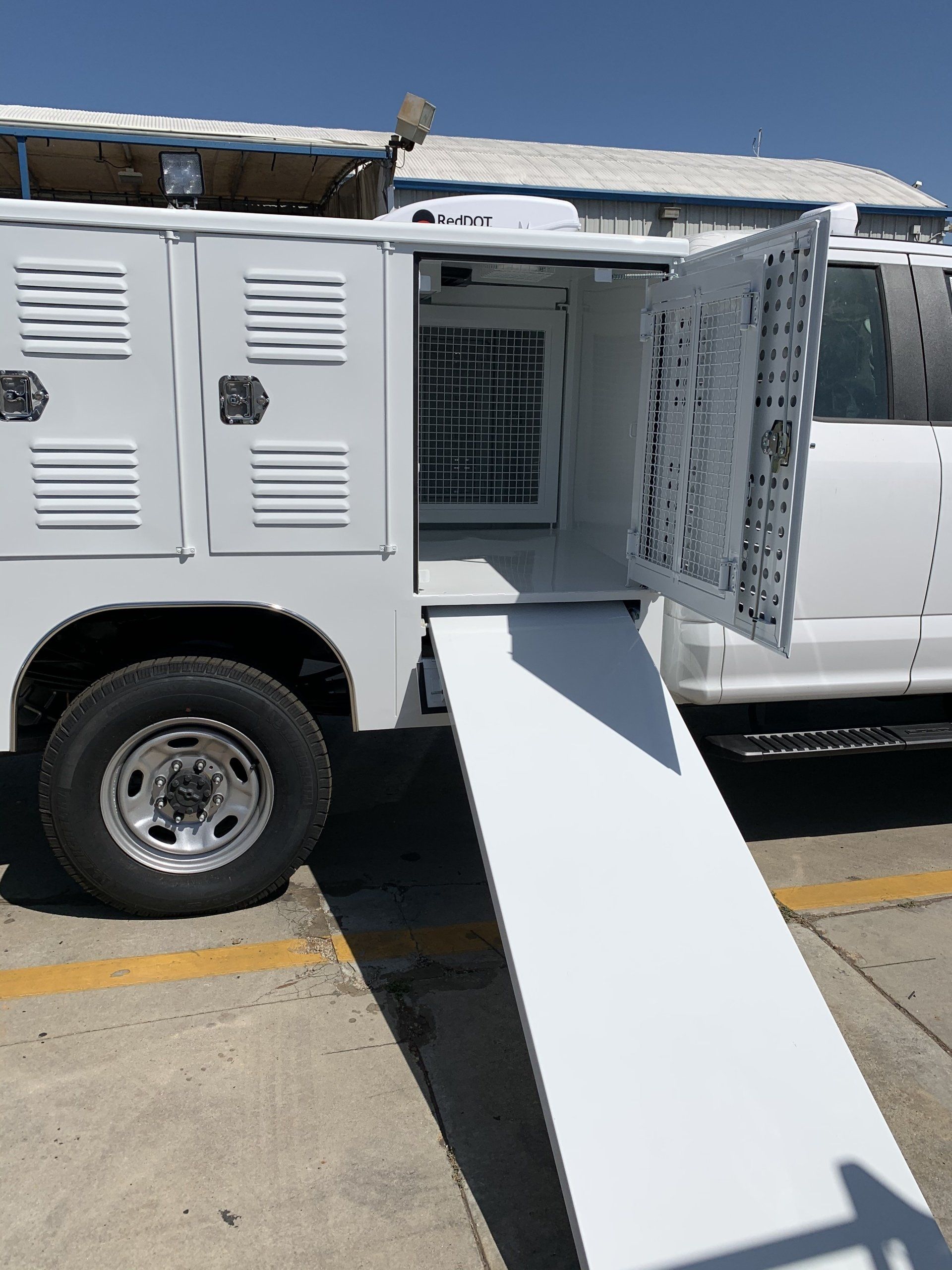White van with open side door and ramp for animal transport.