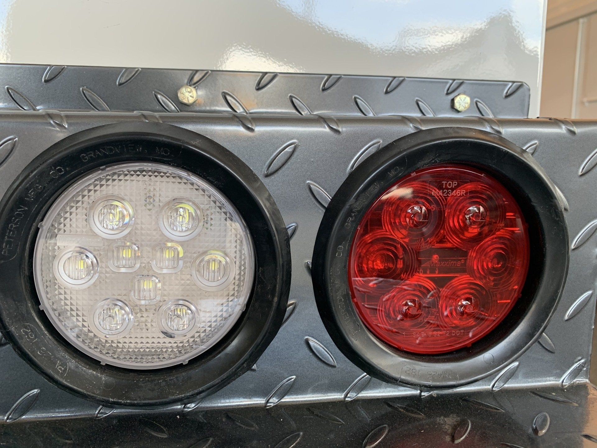 Close-up of trailer lights: white, and red LED lights set in a diamond plate panel.