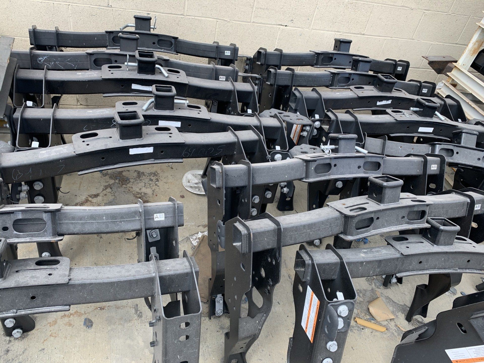 Black metal truck bumper parts stacked outdoors.