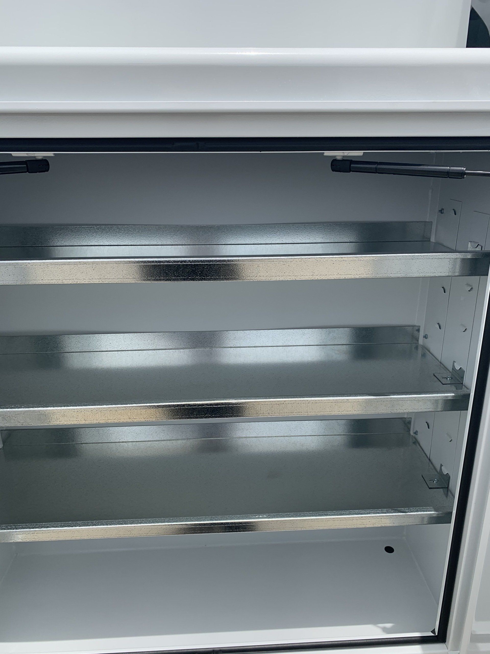 Inside of a white cabinet with three metal shelves.
