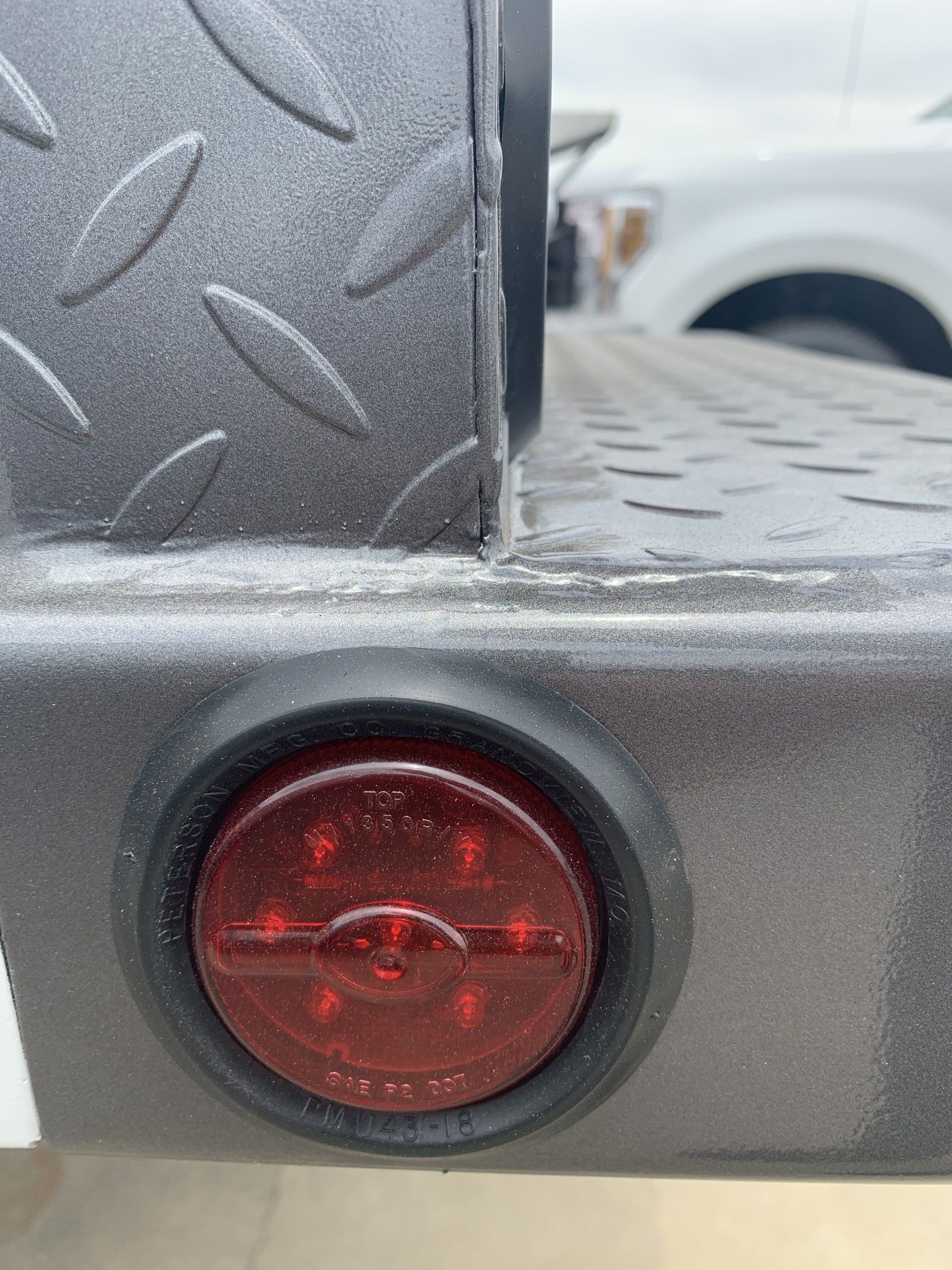 Close-up of a trailer with a red LED light and diamond plate metal.