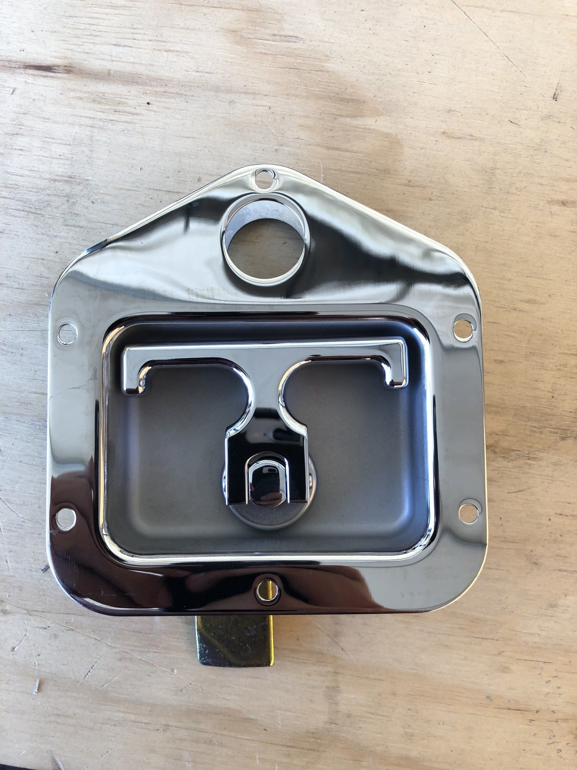 Chrome-plated T-handle latch with a key lock, mounted on wood.