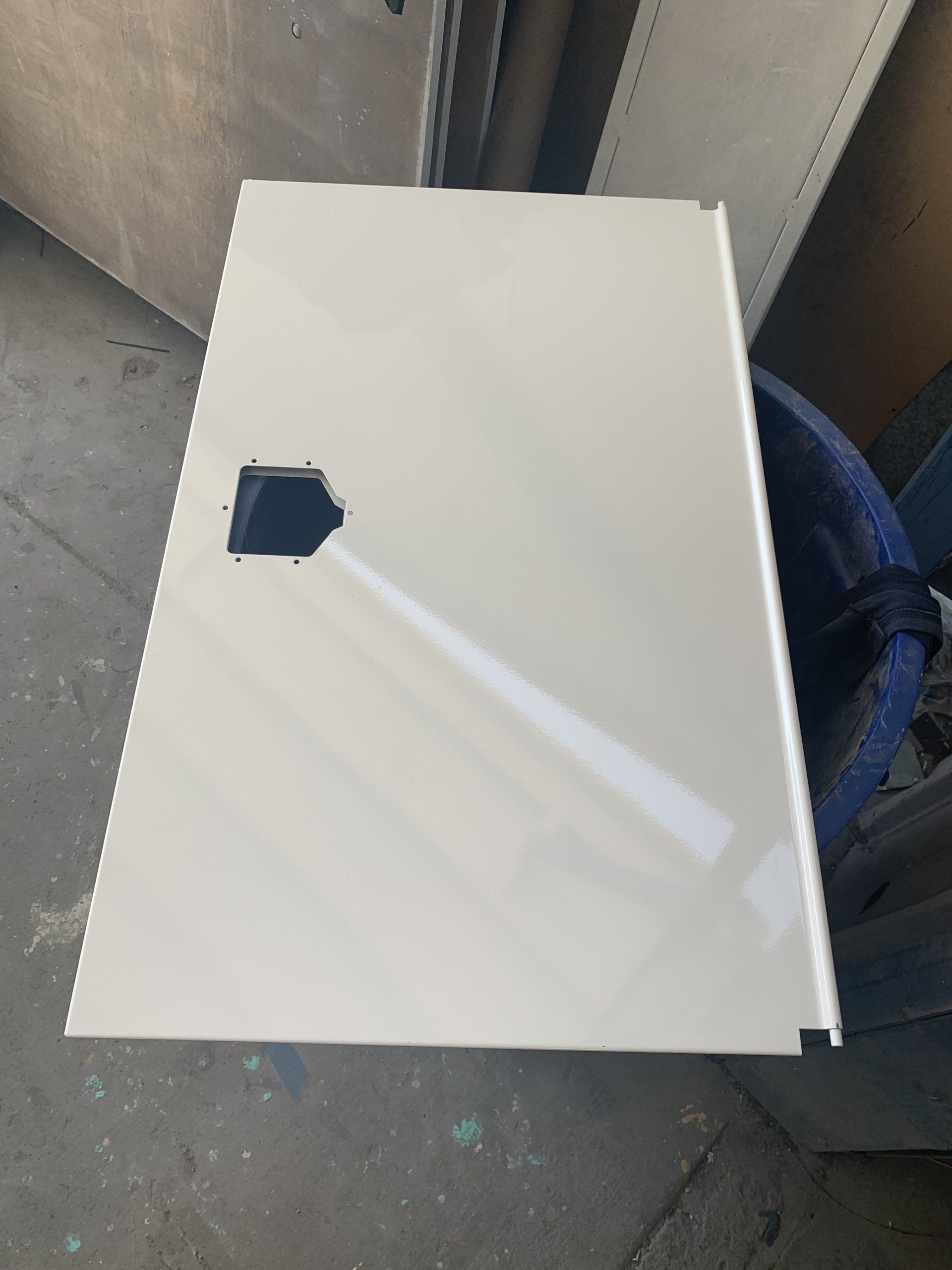 White rectangular metal panel with a black cut-out, likely a door or cover.