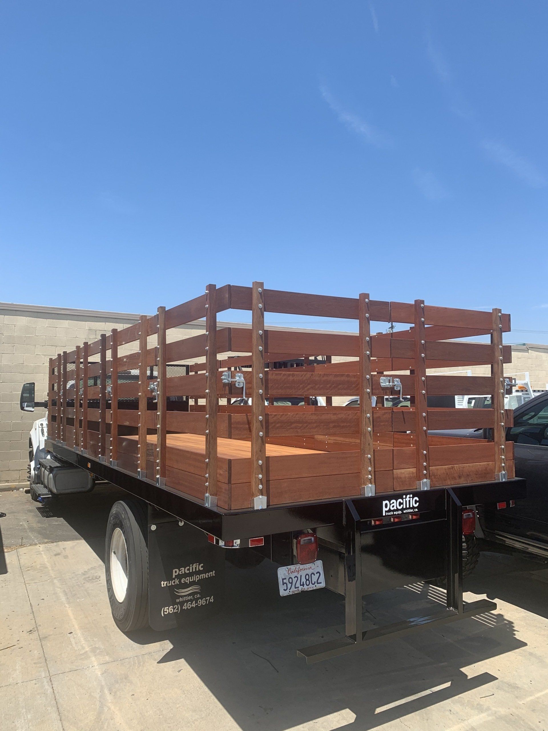 Flatbed truck with wooden sides against a clear blue sky.